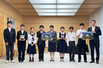 高市内閣総理大臣が中央に立ち、その両脇に学生が数名並んでいる写真