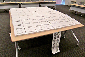 全国から集められた署名が机いっぱいに並べられている