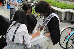 署名活動の様子の写真、女学生が署名を行っている